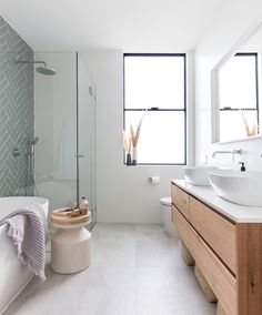 a bathroom with two sinks and a bathtub in the middle, along with large windows