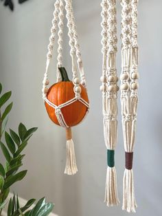 three macrame hangings decorated with pumpkins and tassels on them