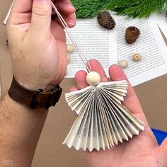 a person holding an ornament in their hand with pine cones on the table