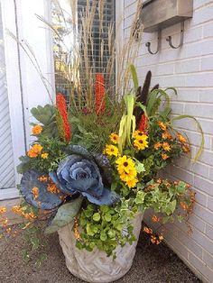 a planter filled with flowers sitting on the side of a building next to a door