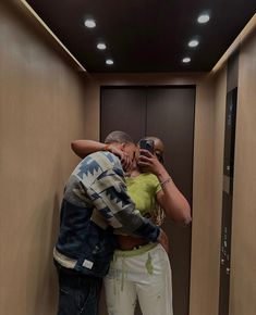 a man and woman taking a selfie in an elevator with their arms around each other