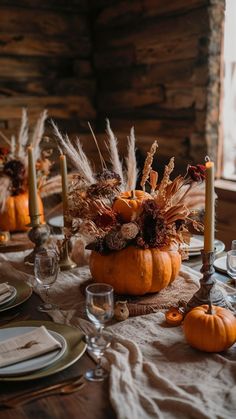 a table set for thanksgiving dinner with pumpkins and pamodia in the center