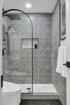 a bathroom with black and white tiles on the walls, flooring and shower stall