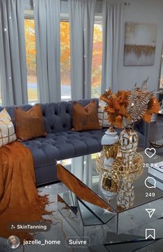 a living room filled with furniture and windows covered in fall leaves on the window sill