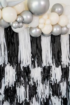 balloons and streamers are hanging from the ceiling in front of a black and white backdrop