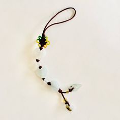 a necklace made with glass beads and bead cord on a white surface, showing the shape of an arrow