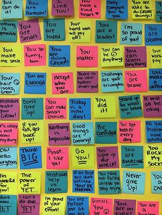 a bulletin board covered in sticky notes with words written on the walls and writing all over it