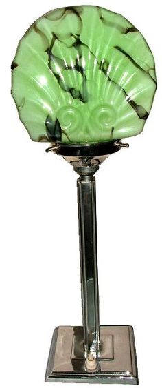 a green glass vase sitting on top of a metal stand