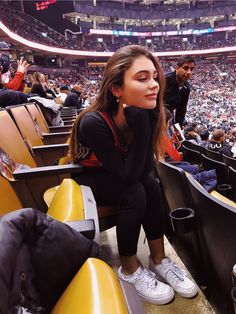 a woman sitting in the stands at a basketball game with her hand on her face