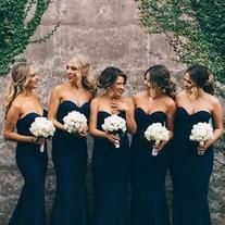 a group of women standing next to each other in front of a wall with ivy growing on it