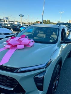 a silver car with a pink bow on it's hood in a parking lot