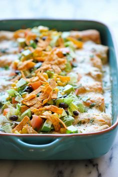 a blue casserole dish filled with vegetables and tortilla chips