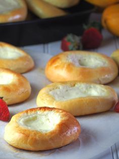 several rolls with cheese and strawberries on the side are ready to be baked in the oven