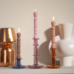 there are three candles on the table next to each other and one candle is pink