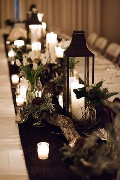 a long table with candles and greenery on it