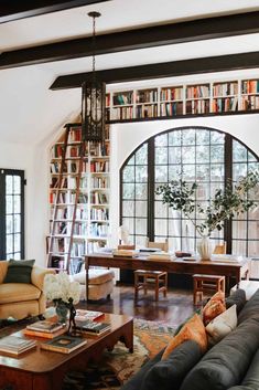 a living room filled with lots of furniture and bookshelves covered in bookcases