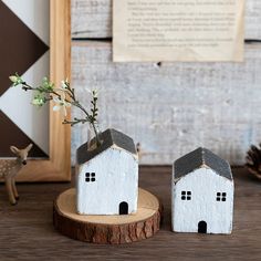 two small white houses sitting on top of a wooden table