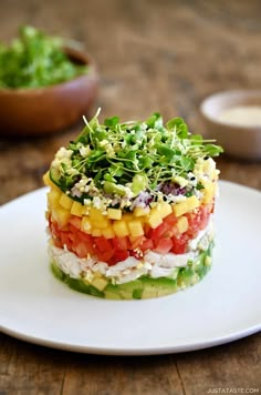 a layered salad on a white plate with lettuce and tomato in the middle