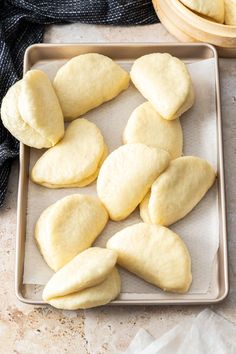 several pieces of bread are on a baking sheet and next to some bowls with napkins