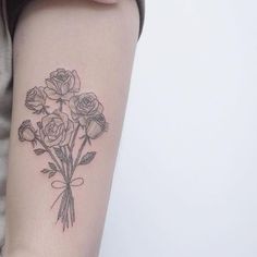 a woman's arm with a bouquet of roses tattoo on the left side of her arm