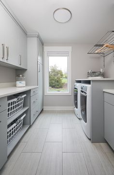 a kitchen with white cabinets and gray appliances in it's center, along with a washer and dryer