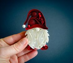 a hand holding an ornament shaped like a gnome's hat on a blue background