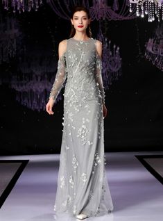 a woman is walking down the runway in a gray dress