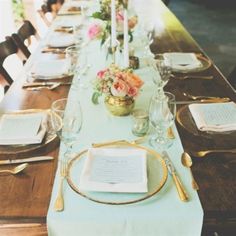 a long table set with place settings and flowers