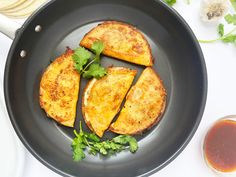 three pieces of fried food in a frying pan next to some dipping sauces