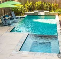 a small pool with lounge chairs and umbrellas next to the side of it in a backyard