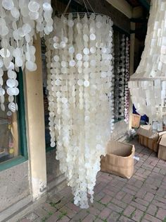 a bunch of white glass beads hanging from the ceiling in front of a store window