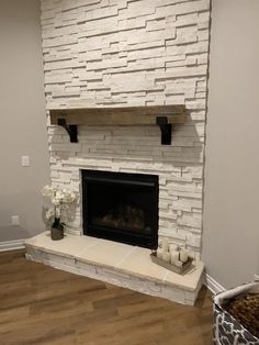 a living room with a fire place and white stone fireplace surrounds in the corner