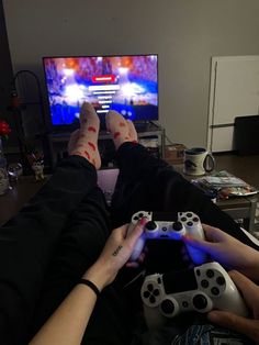 two people are playing video games in front of a tv with their feet on the controllers