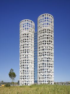 two tall white buildings sitting next to each other on top of a grass covered field