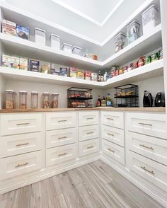 an organized pantry with white cabinets and drawers