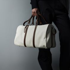 The Modern Canvas Duffle Bag effortlessly blends contemporary style with superior craftsmanship, making it a must-have for both travel and everyday use. Constructed from premium cotton canvas, this bag features PU leather accents that add a touch of sophistication and durability. The base of the bag is reinforced with four rivets, providing extra protection against wear and tear and extending its lifespan. Designed for versatility, it includes a detachable strap, allowing you to carry it as a cr Canvas Duffle Bag With Leather Trim For On-the-go, White Shoulder Bag With Leather Trim For On-the-go, Elegant White Canvas Bag With Large Capacity, On-the-go Weekender Bag With Leather Trim, Luxury Large Capacity White Satchel, Leather Canvas Bag With Large Capacity For On-the-go, Luxury White Rectangular Canvas Bag, White Canvas Bag With Adjustable Strap For Travel, Luxury Coated Canvas Weekender Bag For Everyday