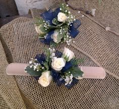 two bridal bouquets with white roses and greenery sit on the back of a chair