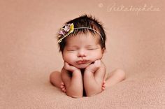 a baby with a flower in it's hair is laying down on a pink blanket