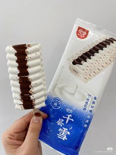 a hand holding a chocolate and white ice cream bar