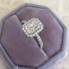 a cushion cut diamond engagement ring in a velvet box with the band around it's edges