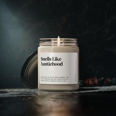 a candle sitting on top of a wooden table next to a black wall with the words smell is like an antithehood written on it