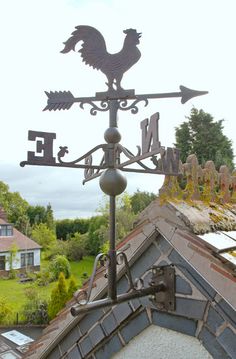 a weather vane on the roof of a house with a rooster design and an arrow