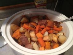 a white bowl filled with potatoes and carrots