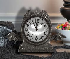 a clock sitting on top of a table next to a bowl of candy