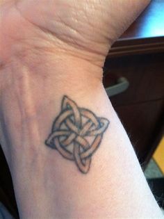 a small tattoo on the wrist of a person's left hand, with an intricate design