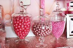 three glass containers filled with candy on top of a counter next to other candies