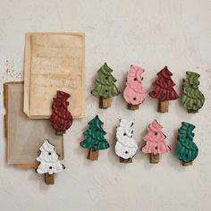 small wooden christmas trees sitting on top of a table next to an old book and envelope