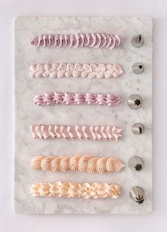 four different types of hair clips on a marble board with buttons and spoons in the middle