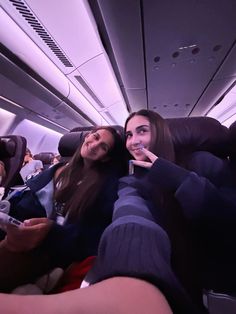 two women sitting on an airplane with toothbrushes in their mouths