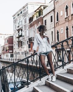 a woman is standing on some steps near the water and buildings in venice, italy